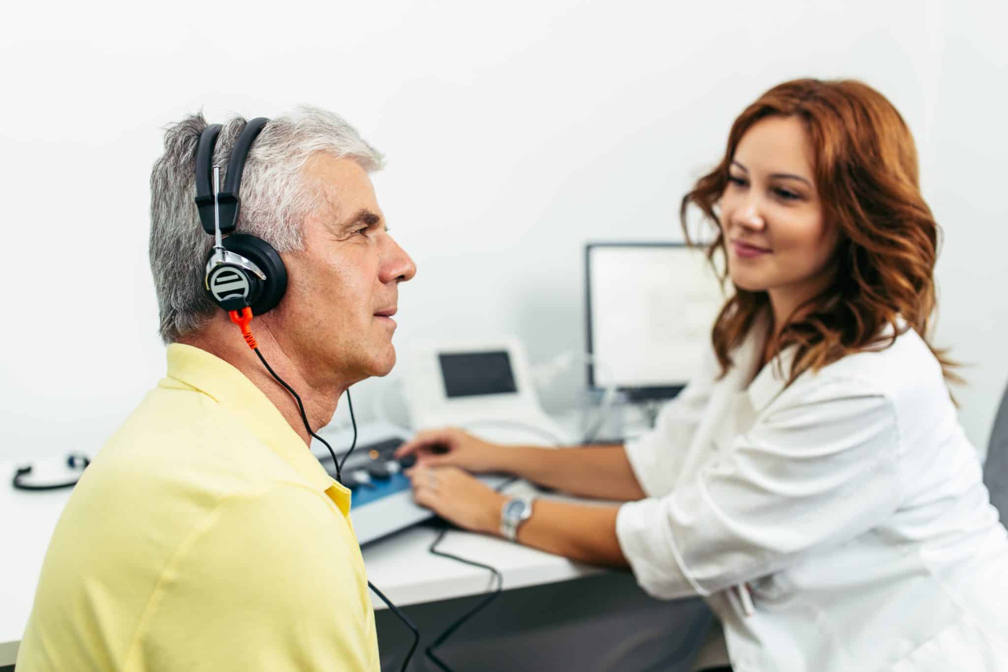 audiology patient completing hearing test Patient with headphones on gets tested for hearing loss by an audiologist